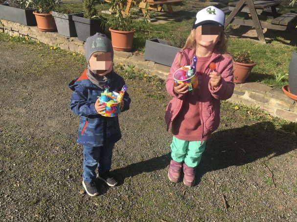 Ein Junge und ein Mädchen stehen im Freien und halten bunte Ostereier in der Hand.